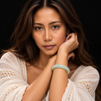 Model wearing a pale green jade bangle bracelet in a softly lit jewellery portrait