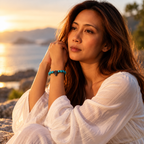 Woman wearing turquoise bead bracelet with Christian cross beside the sea at golden hour