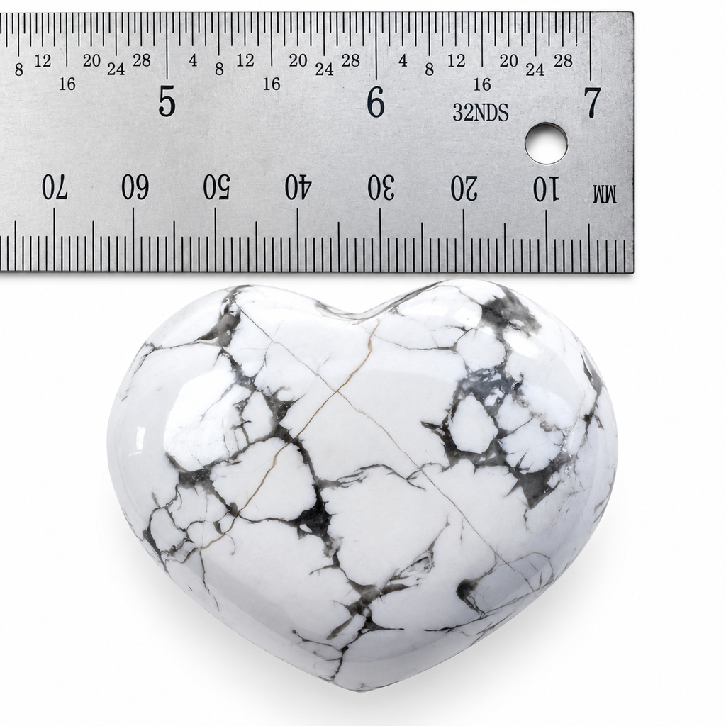 White Howlite heart palm stone with grey marbling beside metal ruler