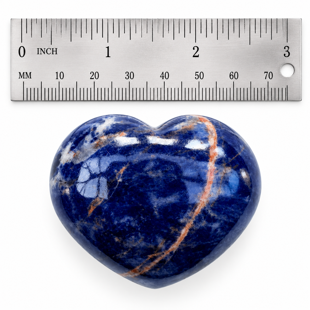Polished blue Sodalite heart palm stone beside metal ruler for size reference