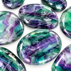 Close-up of polished green and purple Rainbow Fluorite palm stones on white