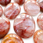 Group of polished Fire Quartz palm stones showing natural variations