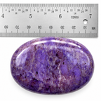Purple Jade palm stone beside a metal ruler for size reference